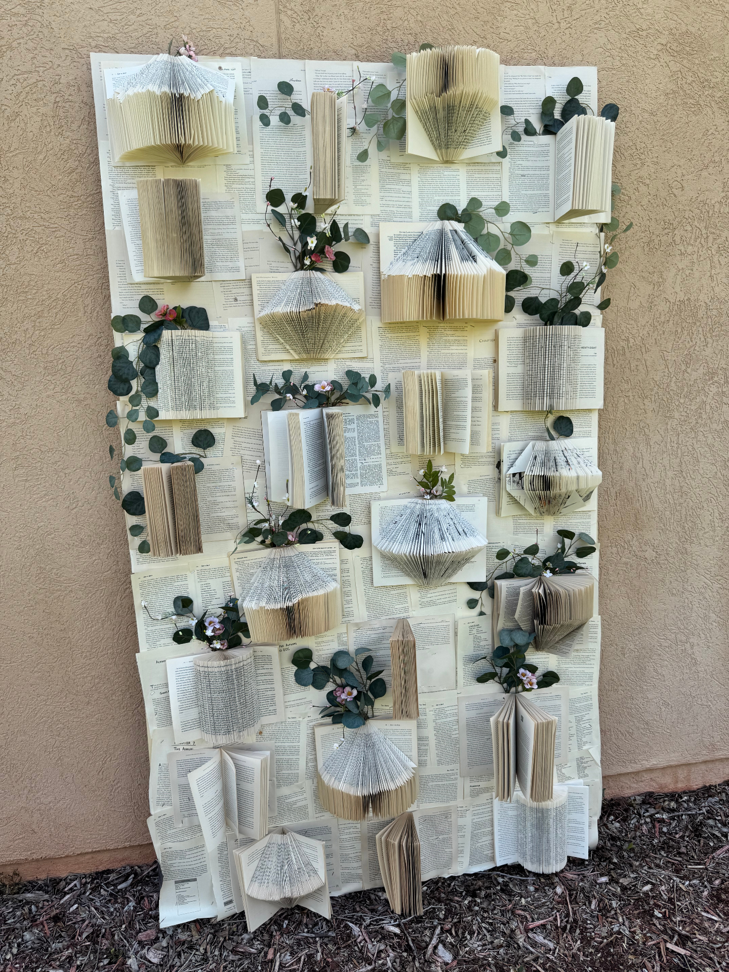 Handcrafted book wall rental with folded pages and greenery